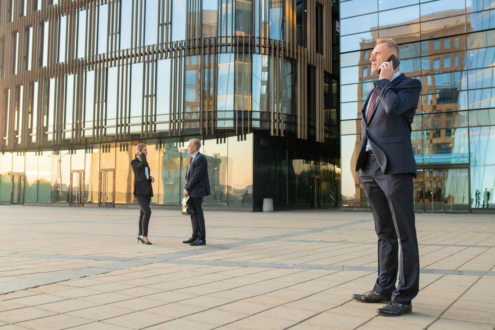 serious confident businessman wearing office suit talking mobile phone outdoors businesspeople city building glass facade background copy space business communication concept scaled